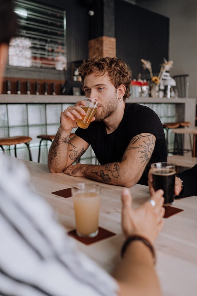 Photograph of a Man in a Black Shirt Drinking Beer