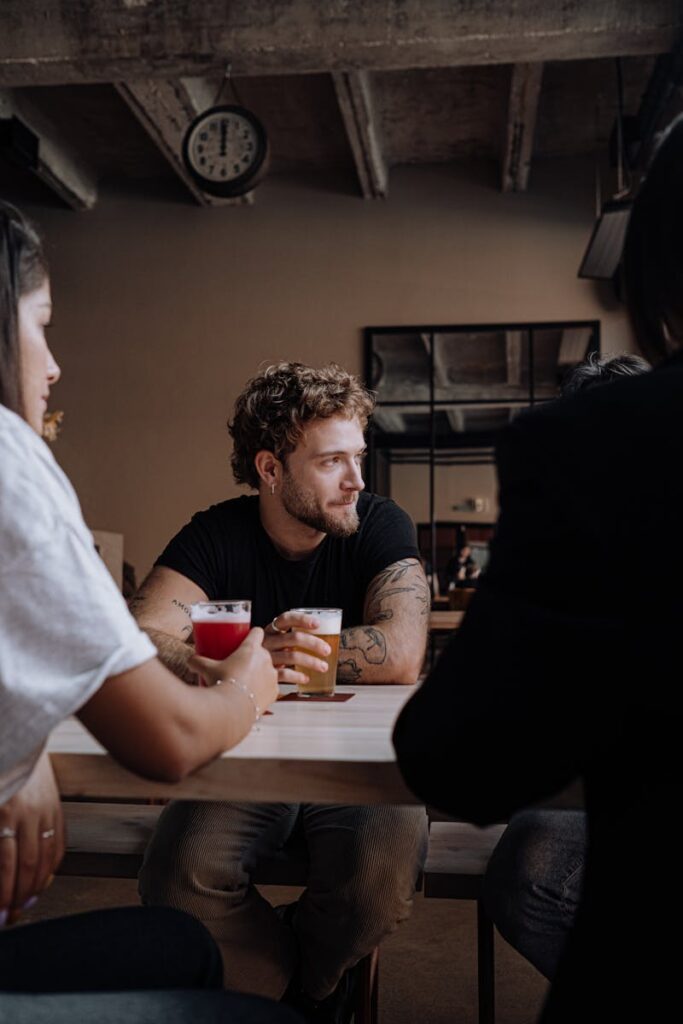 Photo of a Man with Curly Hair Holding a Glass of Beer